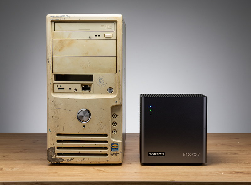 Comparison view of an old desktop PC tower next to a small Topton N100 mini PC on a workbench showing the dramatic size difference between salvage build and modern hardware