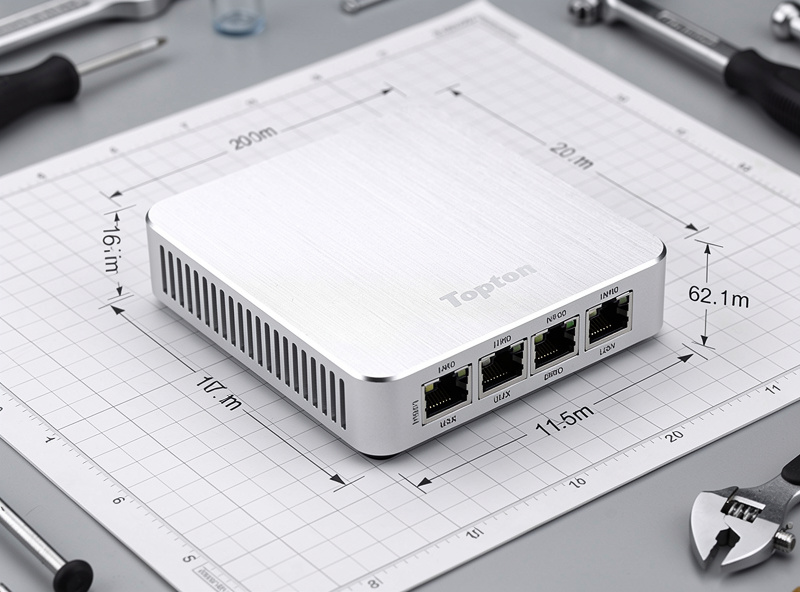 Topton N100 mini PC on a workbench with Ethernet cables connected showing the brushed aluminum enclosure and four Ethernet ports on the back panel