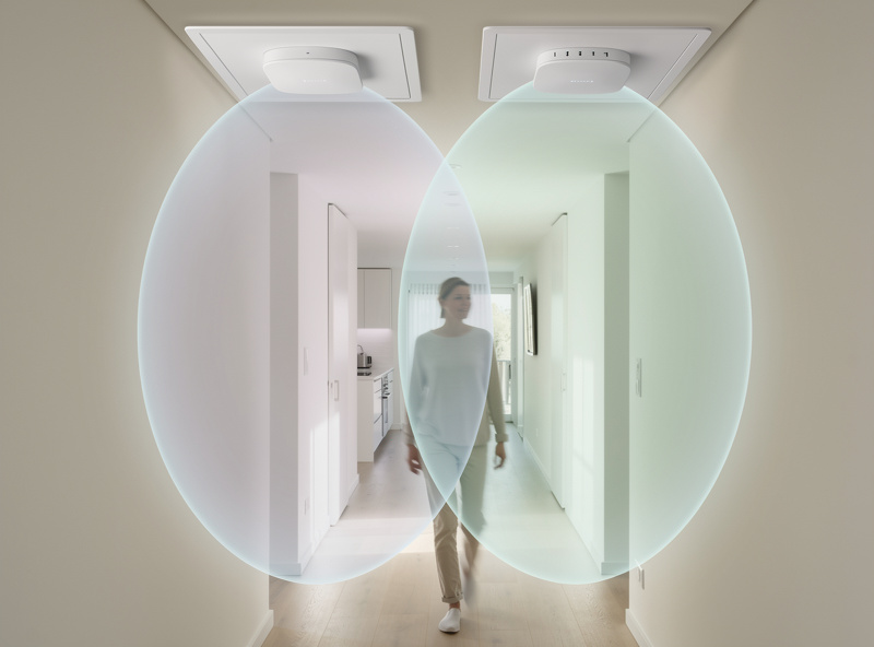 Two ceiling access points with a person walking between their overlapping coverage cells