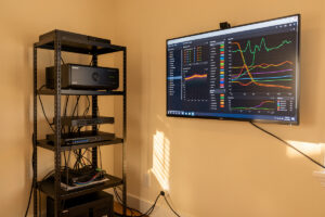 Home network monitoring rack with firewall, managed switch and a wall monitor showing network dashboards