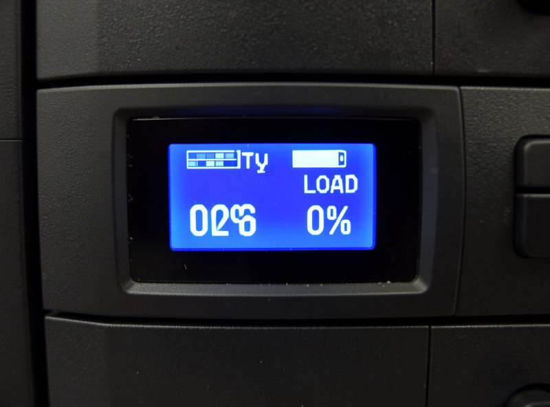 A home lab UPS LCD panel displaying load percentage and estimated runtime in minutes