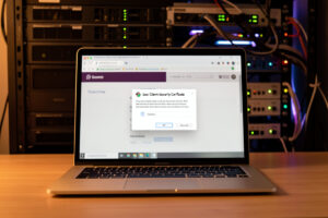 Laptop showing a browser dialog to select a client security certificate with a network rack behind