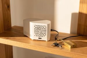 Small fanless home server on a wooden shelf with a brass padlock and key resting nearby in warm light