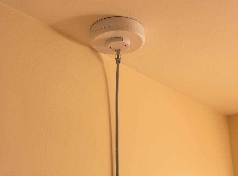 A ceiling access point wired with an Ethernet cable running back through the wall for wired backhaul